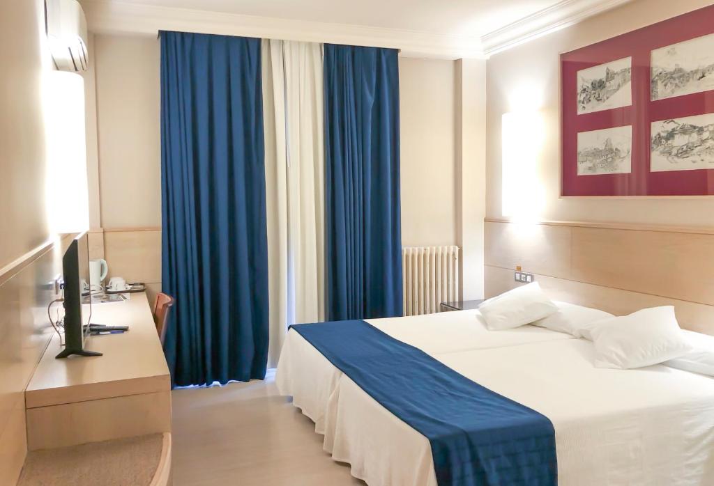 Habitación de hotel con cama y cortinas azules en Hotel Virrey, en Arnedo