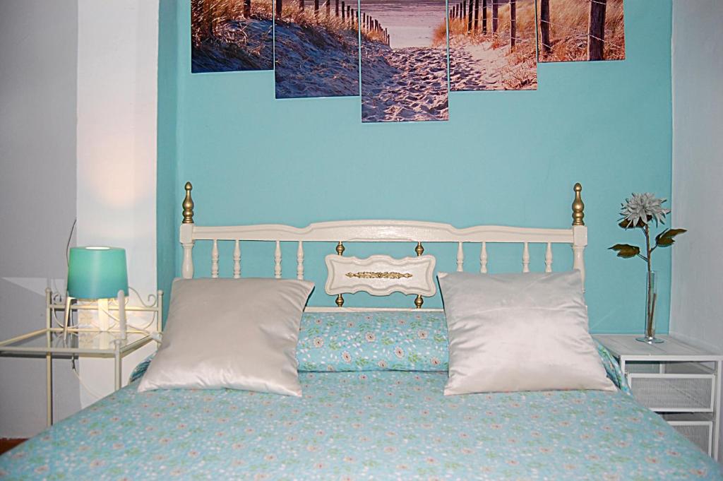 1 dormitorio azul con 1 cama con almohadas blancas en Apartamento San Juan de Dios, en Sevilla