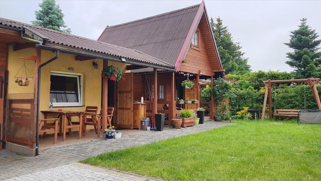 uma casa com um pátio com uma mesa e cadeiras em Domek Wakacyjny Kacperek Drewniany em Stegna
