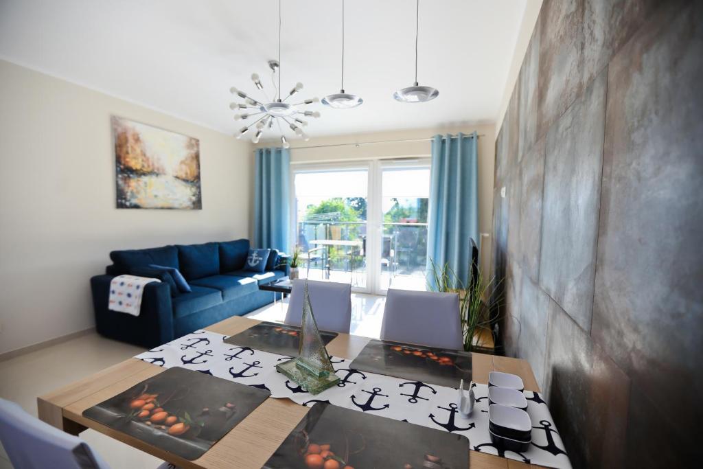 uma sala de estar com uma mesa e um sofá azul em M&K Apartamenty - Marynarski em Gdansk