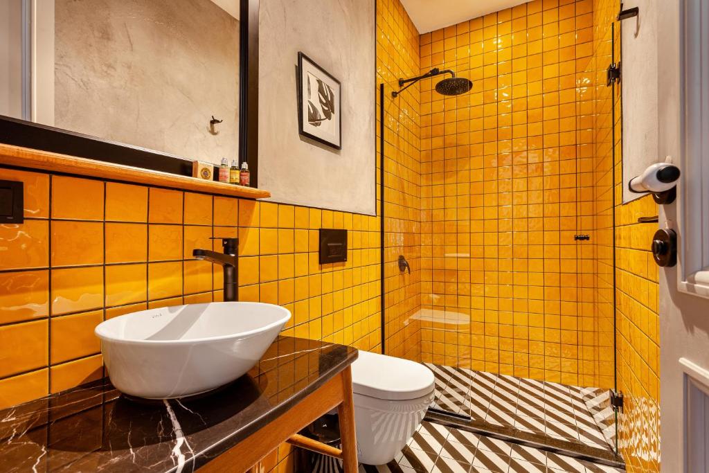 a bathroom with a sink and a toilet and yellow tiles at World House Boutique Hotel Galata in Istanbul