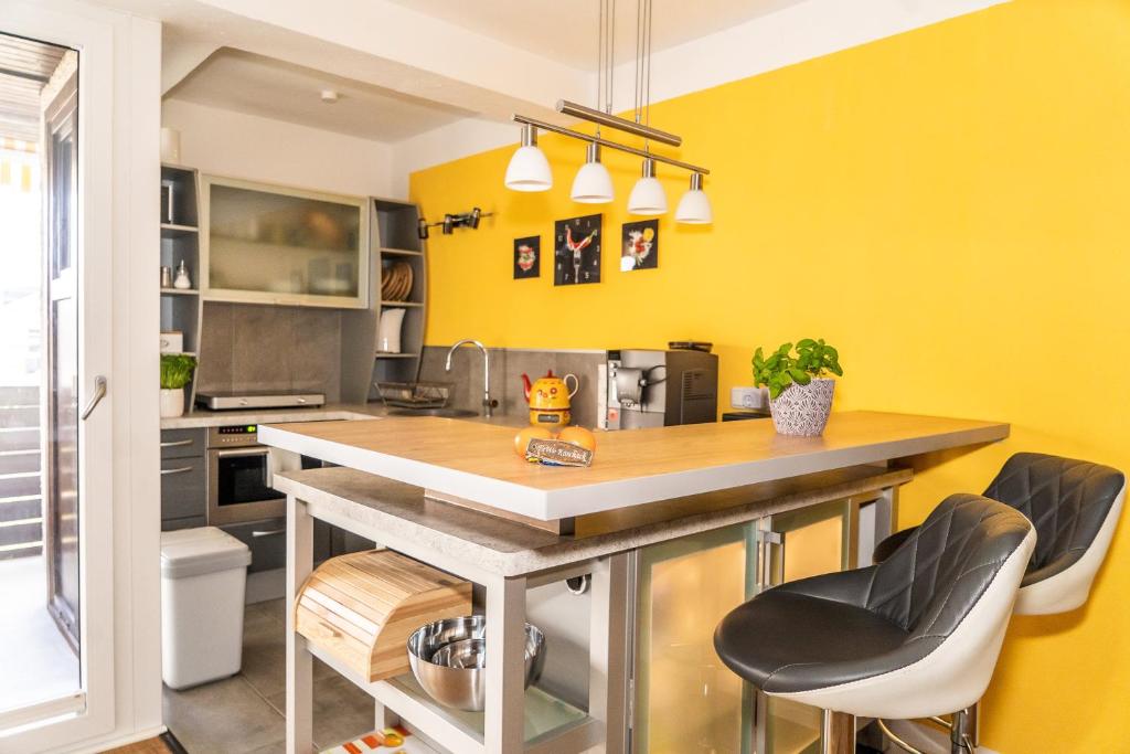 eine Küche mit gelben Wänden und einer Theke mit Hockern in der Unterkunft Ein Zimmer Apartment Bernau mit großer Garage incl in Bernau am Chiemsee
