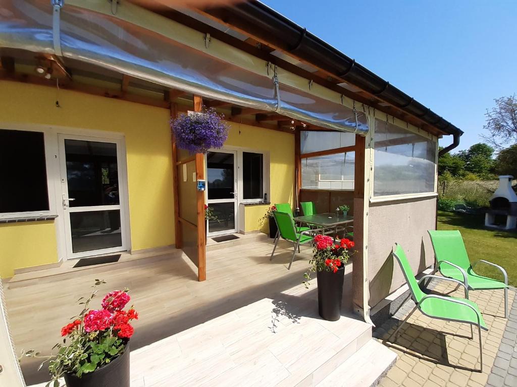 a house with a deck with green chairs and flowers at Domki ANNA in Rewal