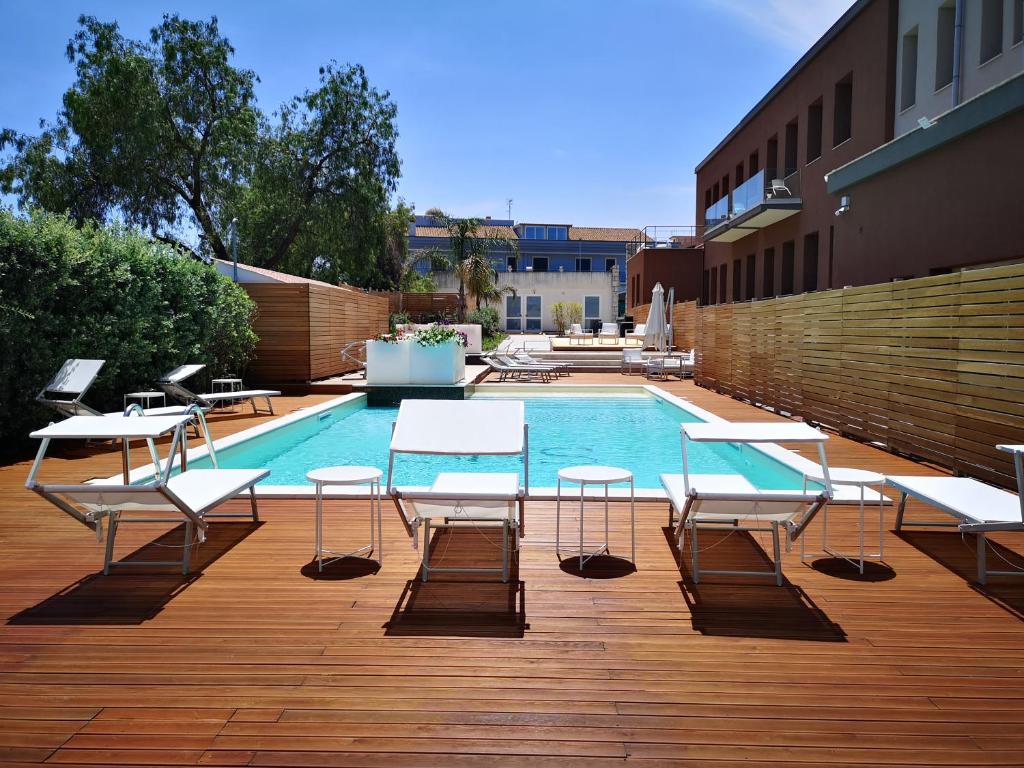 a pool with tables and chairs next to a building at Sicilia Hotel Spa in Giarre