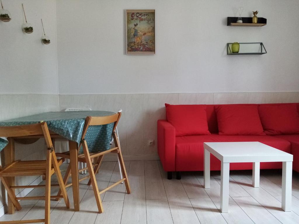 sala de estar con sofá rojo y mesa en La Cabine, en Trouville-sur-Mer