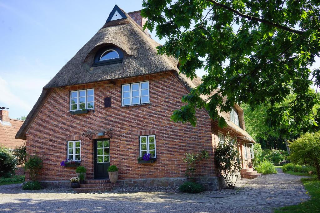 une maison en briques rouges avec un toit de chaume dans l'établissement "Haus auf dem Berg", à Westensee