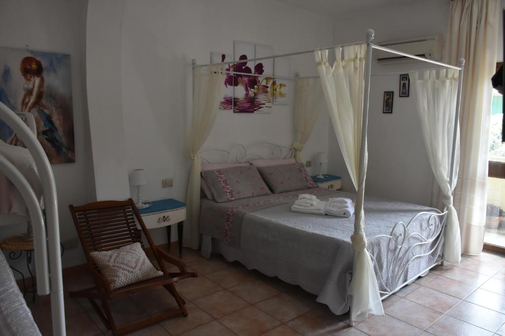 ein Schlafzimmer mit einem Bett und einem Stuhl in der Unterkunft Bed and Breakfast Le petunie in Bari Sardo