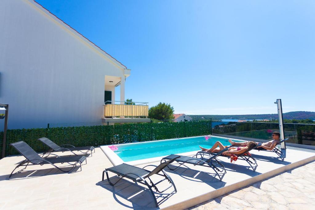 a woman laying in a chair next to a swimming pool at Apartment Jerry with private pool in Milna