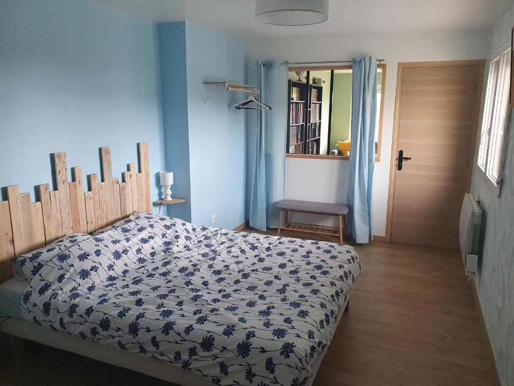 een slaapkamer met een bed met een blauw en wit dekbed bij L'abri côtier in Équihen-Plage