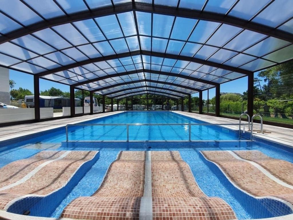 a swimming pool with a glass roof and a swimming poolvisor at Hotel Arco Iris in Villanueva de Arosa