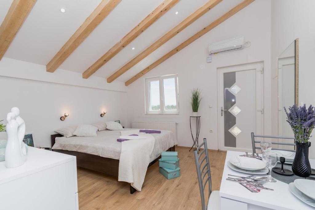 a white bedroom with a bed and a table at Studio Apartment Harmony NP Krka in Lozovac