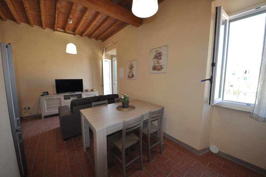 a living room with a table and chairs and a television at Casa dei canali, sulla piazza del paese in Capoliveri