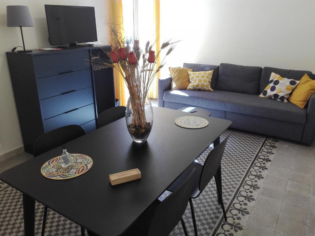 un salon avec une table et un vase de fleurs dans l'établissement "RUNFULÌA" DELUX apartment, à Palerme