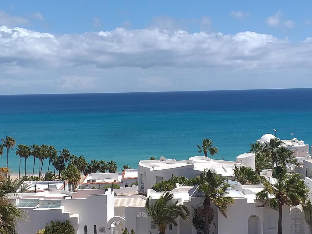 a white building with the ocean in the background at Casa Kristin (WLAN gratis) in Costa Calma
