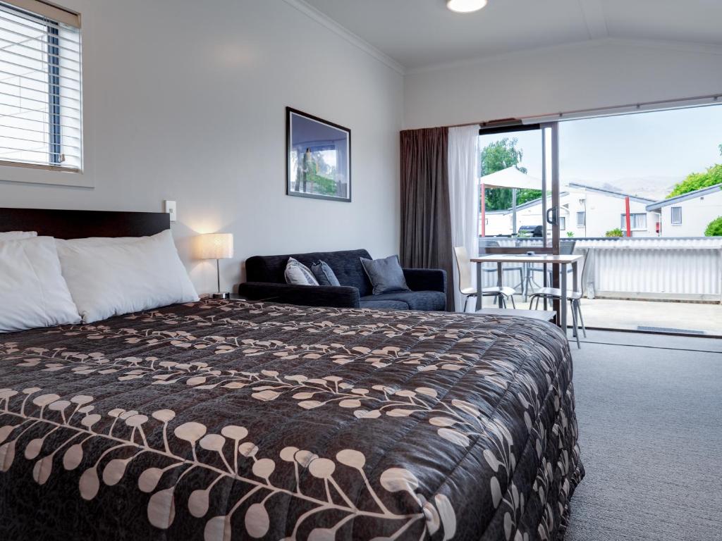 een slaapkamer met een bed, een bank en een balkon bij Anderson Park Motel in Cromwell