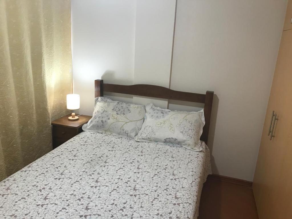 1 dormitorio con 1 cama y 1 lámpara en una mesa en Apartamento no Alto de Teresópolis próx. Faculdade FESO en Teresópolis