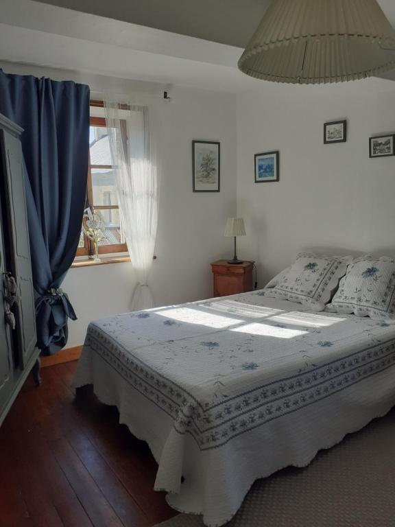 a bedroom with a bed with a blue curtain and a window at Maison Normande in Asnelles