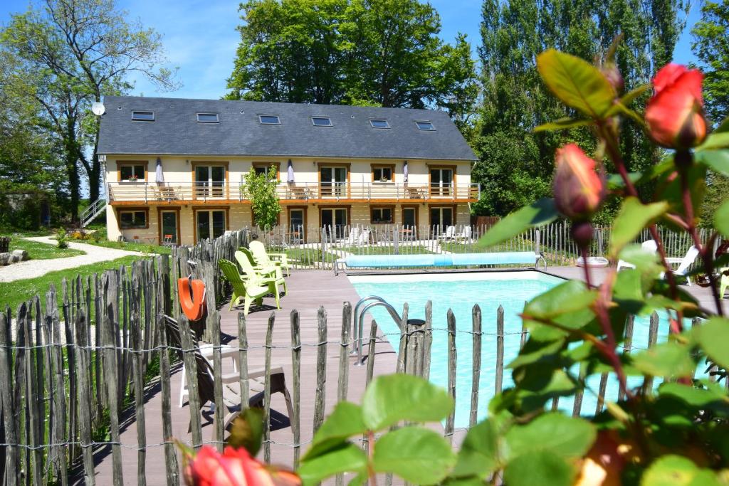 a house with a swimming pool in front of a fence at Le Relais du Hibou in Vittefleur