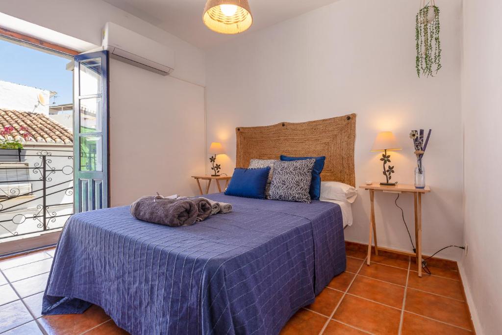 a bedroom with a bed with a blue comforter at Casa Randonneur, traditional townhouse in Álora. in Alora