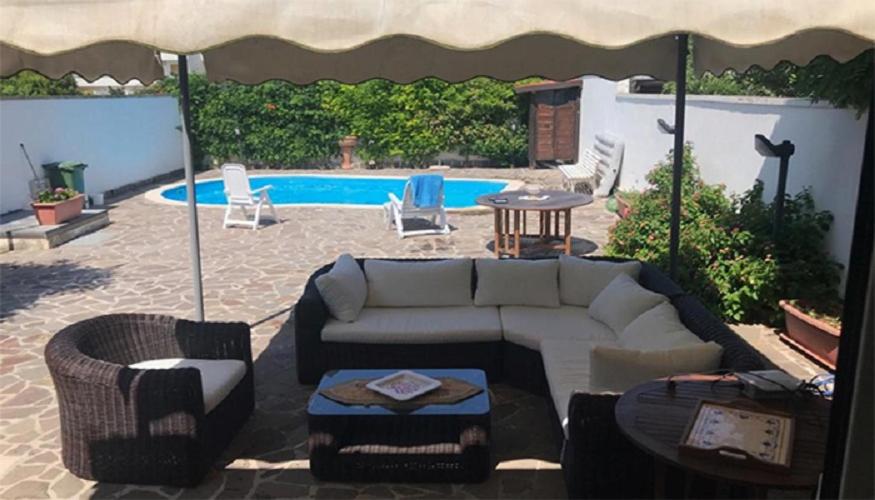 un patio con divano e sedie e una piscina di Villa con piscina - Pt54 a Torre dell'Orso