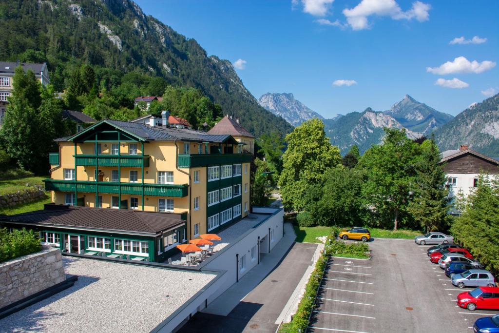 a building with a parking lot and mountains in the background at Landhotel Post Ebensee am Traunsee ***S in Ebensee