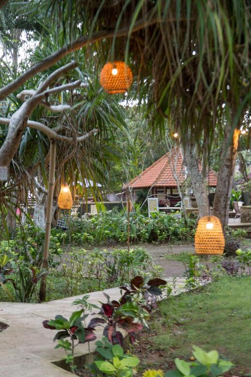 two orange lights hanging from trees in a garden at Rasasvada cottages in Uluwatu