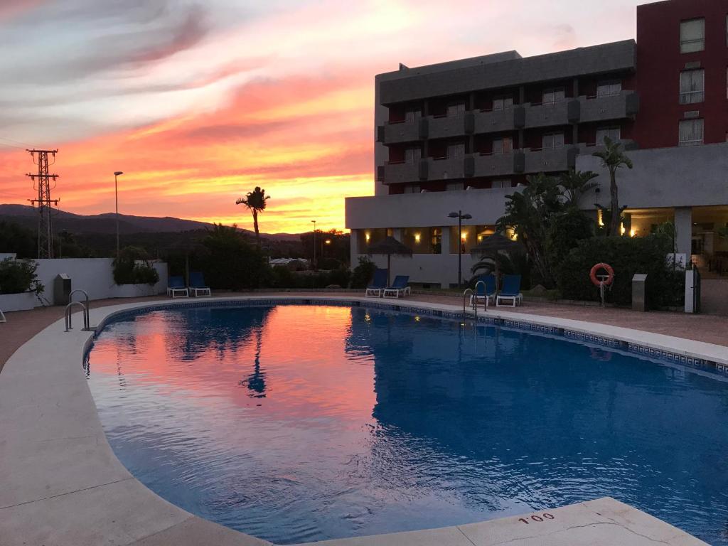 a large swimming pool with a sunset in the background at Hotel Montera Plaza in Los Barrios