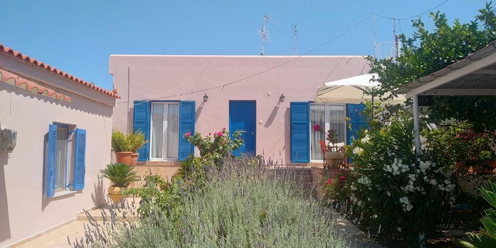 a house with blue shutters and a yard with plants at Aegina House in Aegina Town