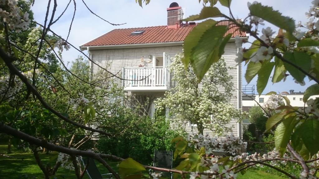 a white house with a balcony and trees at Ljust boende, egen ingång och trädgård i centrum in Varberg