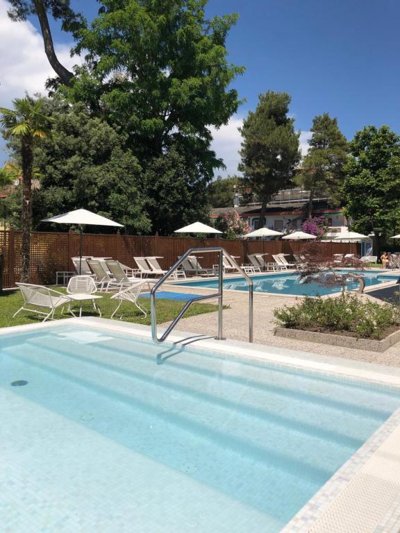 una grande piscina con sedie e ombrelloni di Hotel Mar Del Plata a Grado