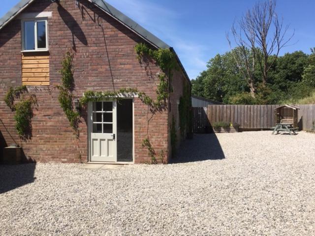 a brick building with a door in a gravel yard at Harepath Farm Cottages 2 in Exeter