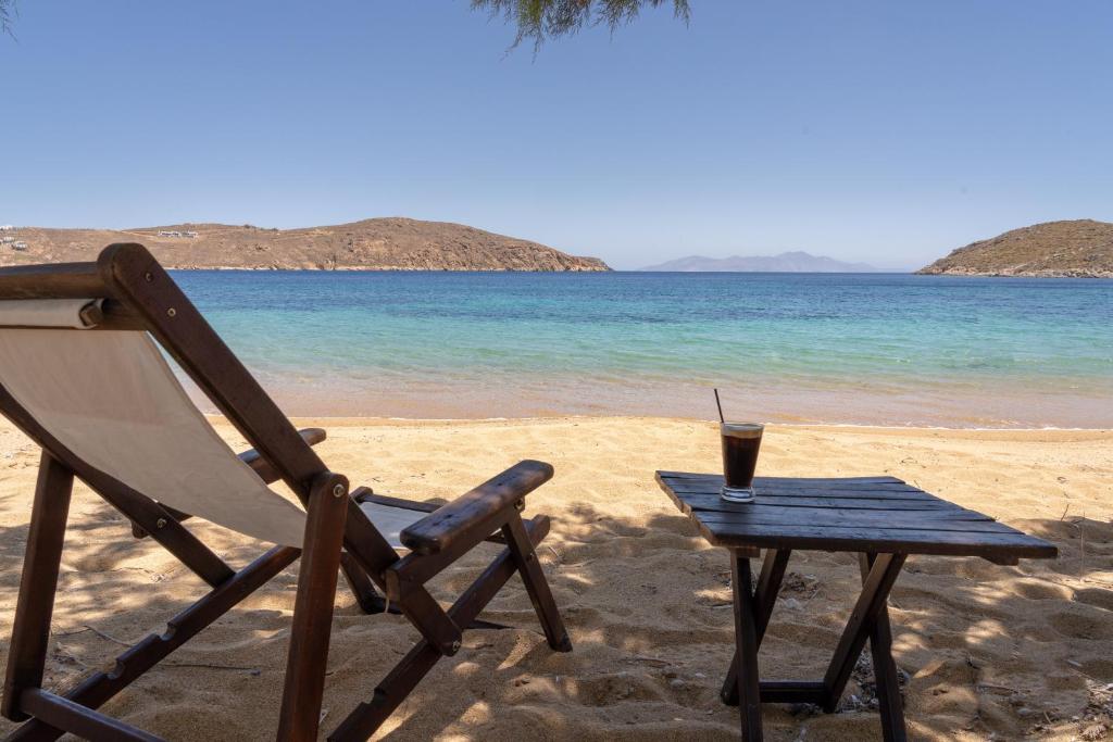 a chair and a table with a drink on the beach at Alexandros by the Beach - Serifos in Livadakia