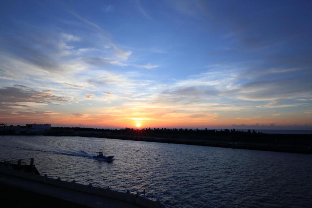 un bateau sur une rivière avec le coucher du soleil en arrière-plan dans l'établissement Min Le Yuan B&B, à Hualien