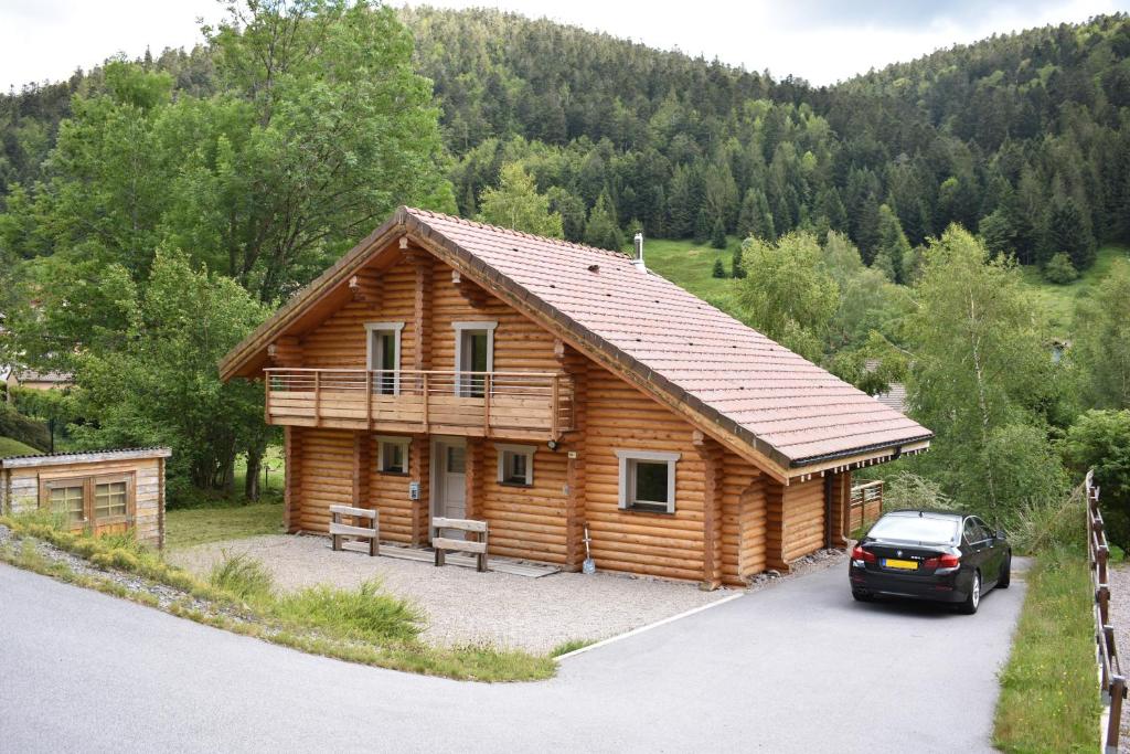 una cabaña de madera con un coche aparcado delante de él en Le Chardonneret, en La Bresse