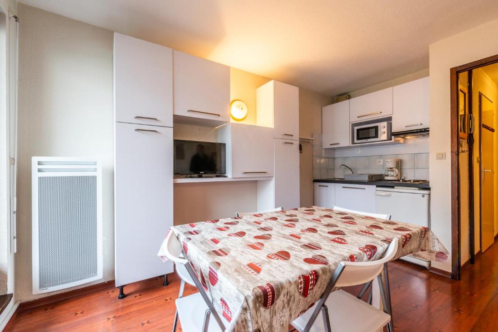 a kitchen with white cabinets and a table with chairs at Meilleur emplacement hypercentre avec parking privatif souterrain in Chamonix