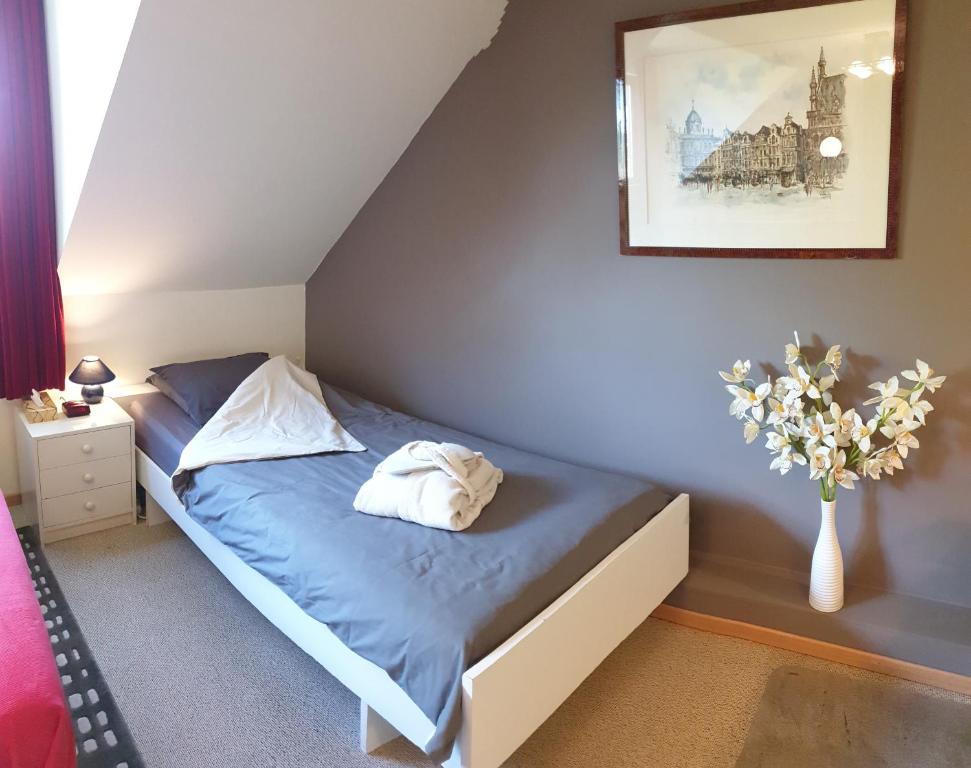 ein Schlafzimmer mit einem Bett und einer Vase aus Blumen in der Unterkunft Be.Cosy in Brüssel