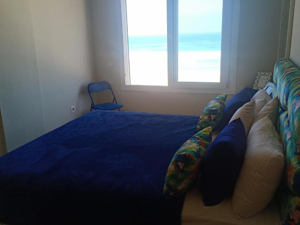 a bedroom with a bed with a blue blanket and a window at Appartement plage mehdia in Kenitra
