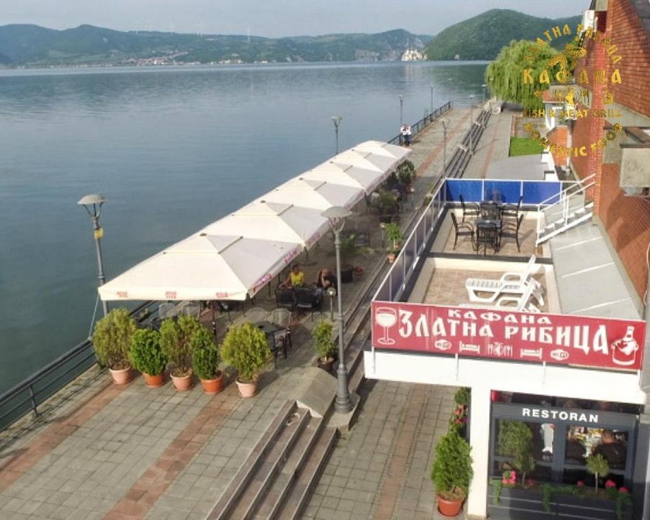 a restaurant on the side of a river with water at Zlatna Ribica in Golubac