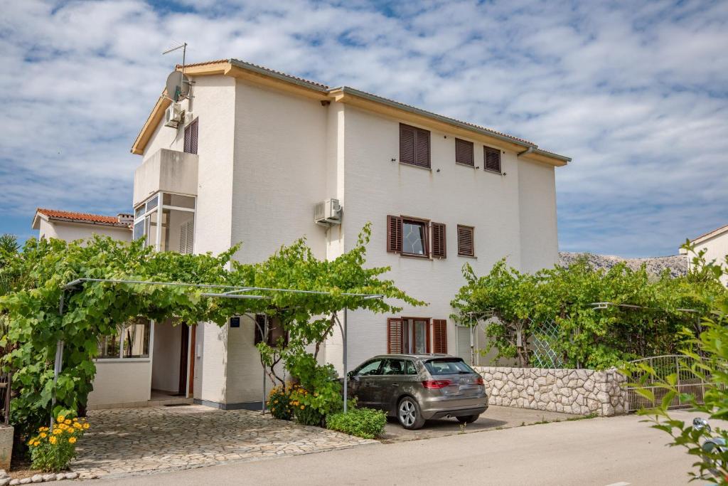 a house with a car parked in front of it at Apartman Lana in Baška
