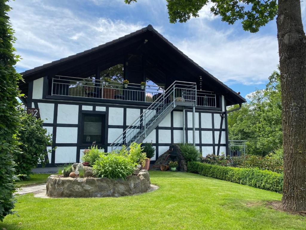 uma casa a preto e branco com uma varanda em Ferienwohnung Zur Parmke em Schmallenberg