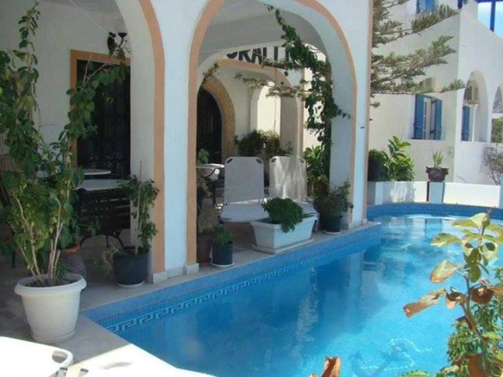 a house with a swimming pool with potted plants at Hotel Koralli in Kamari