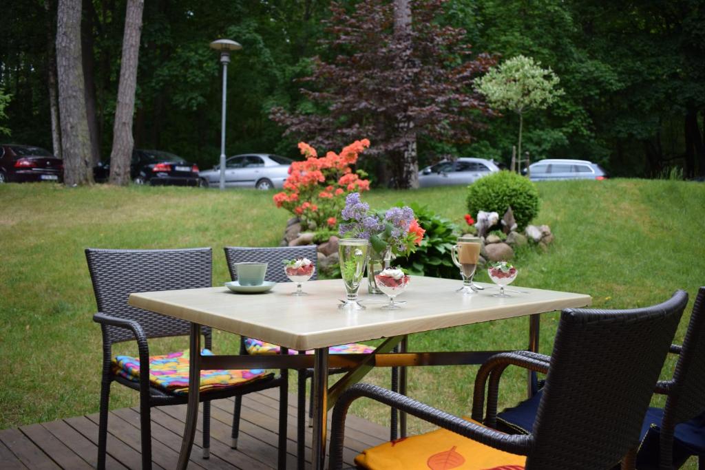 una mesa y sillas con copas de vino y flores en Kalnas apartaments, en Juodkrantė