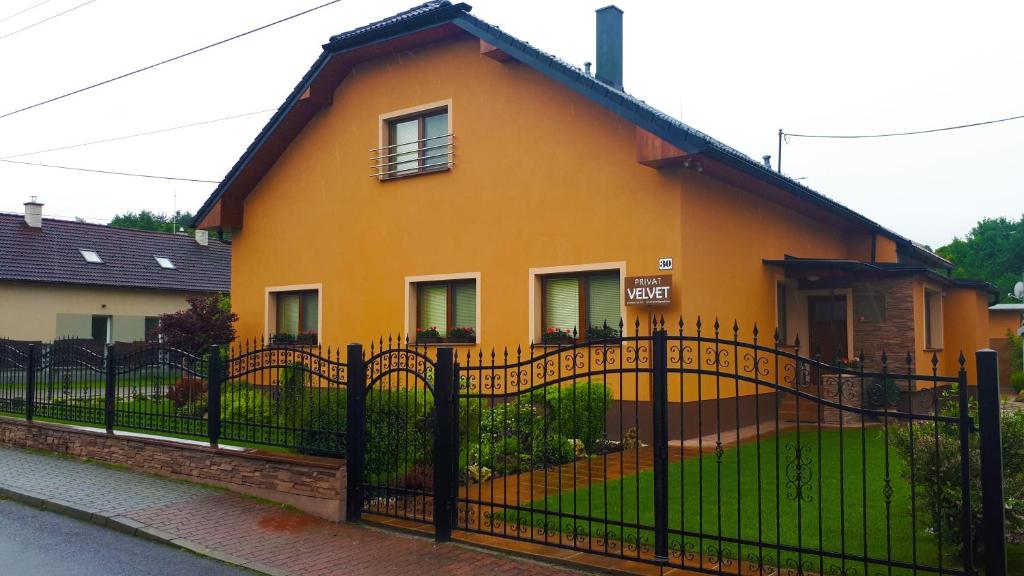 una casa amarilla con una valla negra delante de ella en Privat Velvet, en Turčianske Teplice