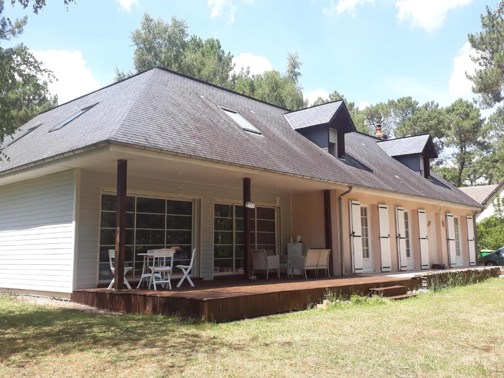 una casa con techo inclinado y terraza en B&B La Forêt de Charmeuse, en Ruaudin