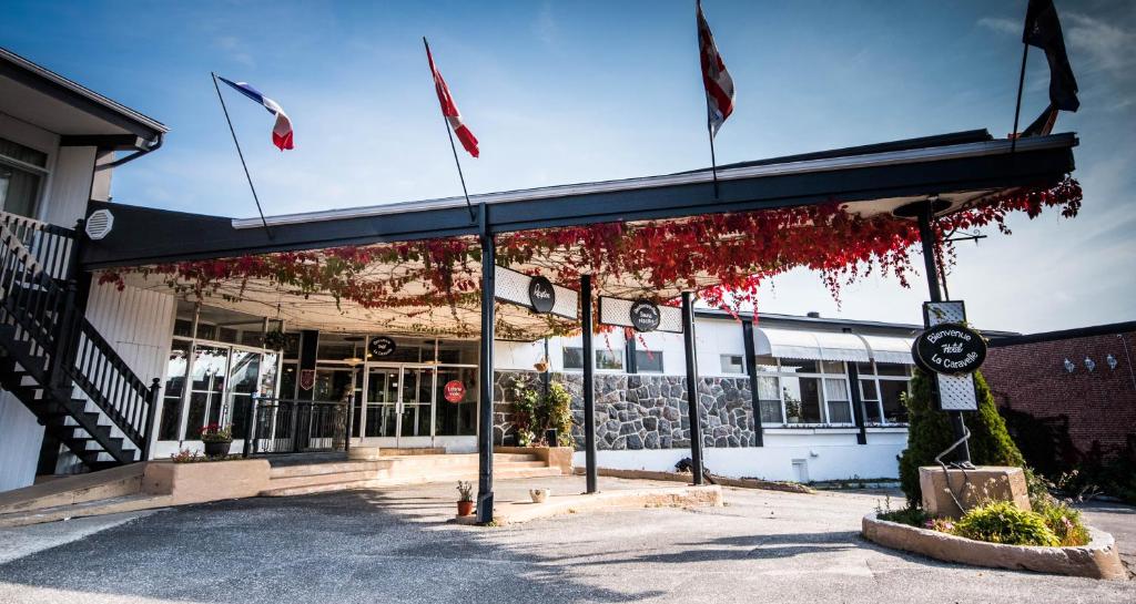 a building with american flags in front of it at Hotel La Caravelle in Baie-Comeau