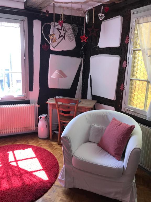 - un salon avec une chaise blanche et un tapis rouge dans l'établissement Gîte Au Fil Du Temps, à Colmar