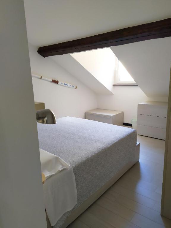 a white bedroom with a bed and a window at La mansarda sul Porto in Camogli