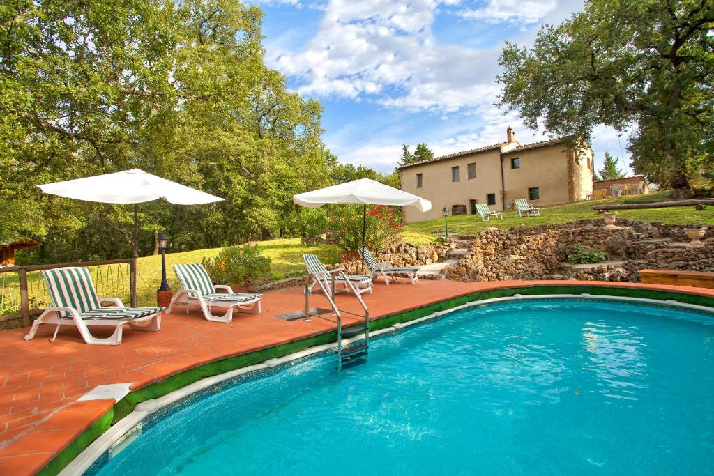 einen Pool mit 2 Stühlen und 2 Sonnenschirmen in der Unterkunft Villa vicino Siena con piscina e molto verde - solo per Voi in Sovicille