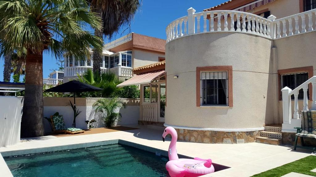 un cisne rosa en una piscina frente a una casa en villa en torre de la horadada a 240m de la playa, en Torre de la Horadada