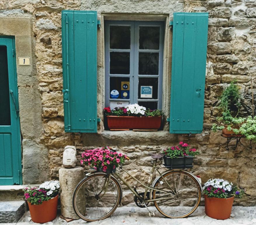 a bike parked in front of a building with flowers at Gite les Volets Verts in Cesseras